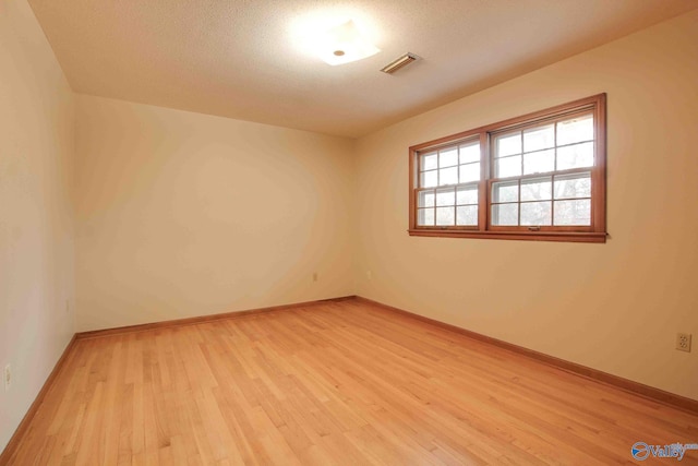 spare room with a textured ceiling and light wood-type flooring