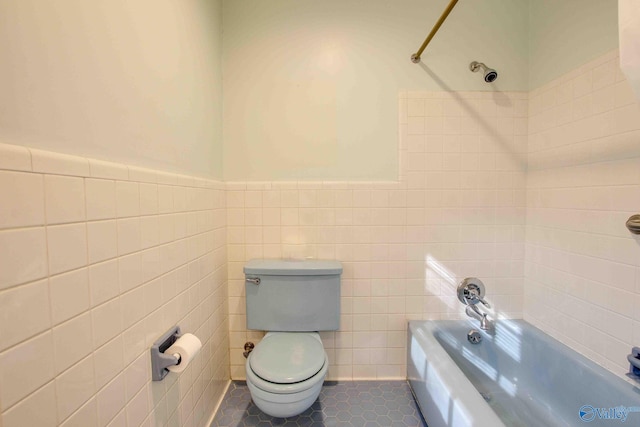 bathroom featuring tile patterned floors, tile walls, tiled shower / bath combo, and toilet