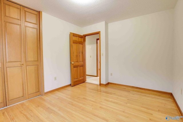 unfurnished bedroom with a closet, a textured ceiling, and light wood-type flooring