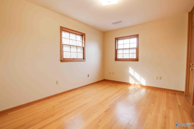 spare room featuring a healthy amount of sunlight and light hardwood / wood-style floors