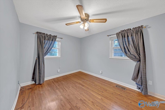 spare room featuring light wood-type flooring, a healthy amount of sunlight, visible vents, and baseboards