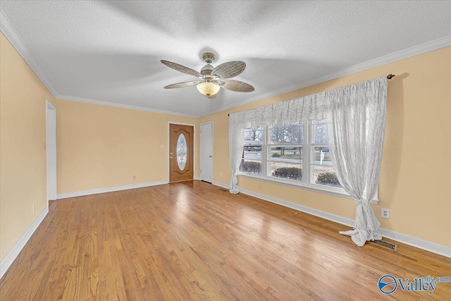 interior space with a textured ceiling, ceiling fan, wood finished floors, baseboards, and crown molding