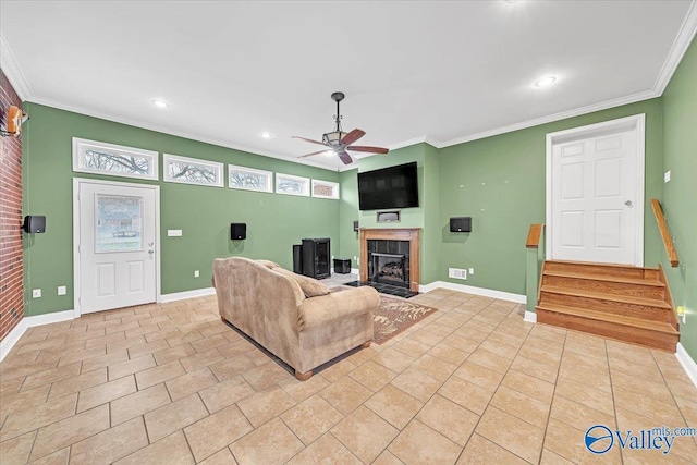 living room with ceiling fan, a fireplace, baseboards, and crown molding