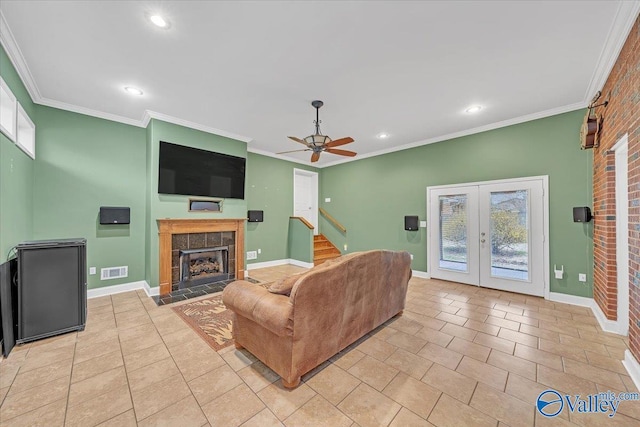 living area featuring light tile patterned flooring, visible vents, crown molding, and a tile fireplace