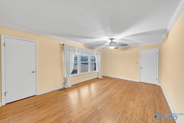 empty room featuring ceiling fan, a textured ceiling, light wood-style flooring, visible vents, and ornamental molding