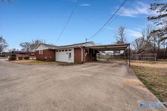 view of front of home featuring driveway, fence, a carport, and brick siding