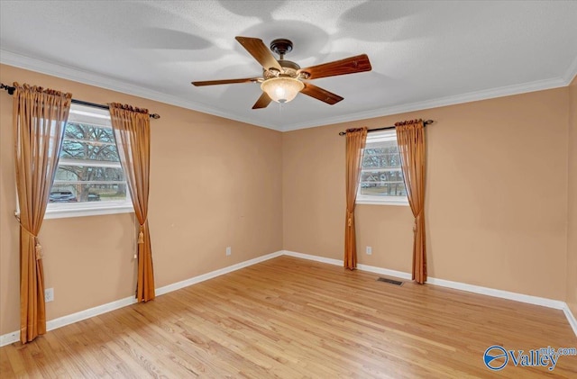 empty room featuring ornamental molding, baseboards, visible vents, and light wood finished floors