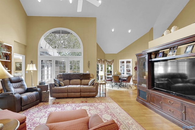 living room with ceiling fan, light wood-type flooring, high vaulted ceiling, and a healthy amount of sunlight