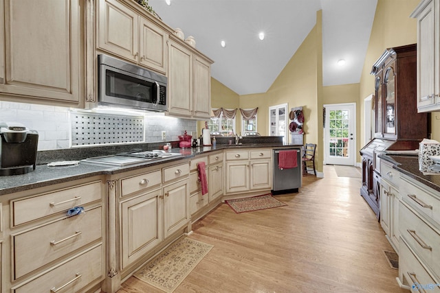 kitchen with decorative backsplash, light hardwood / wood-style flooring, high vaulted ceiling, light brown cabinetry, and appliances with stainless steel finishes