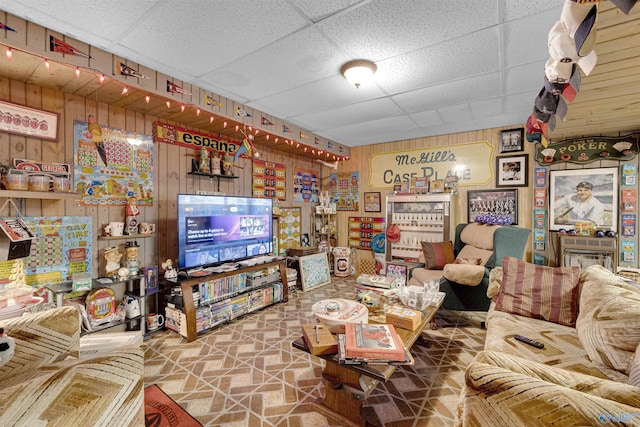 living room with a drop ceiling and wooden walls