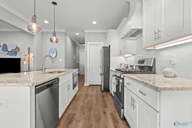 kitchen with custom exhaust hood, stainless steel appliances, sink, white cabinets, and hanging light fixtures