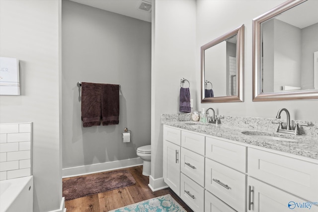 bathroom featuring hardwood / wood-style floors, vanity, toilet, and a tub to relax in