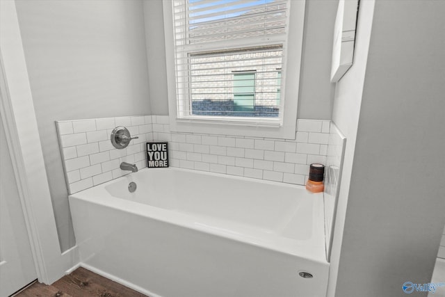 bathroom with hardwood / wood-style flooring, plenty of natural light, and a tub to relax in