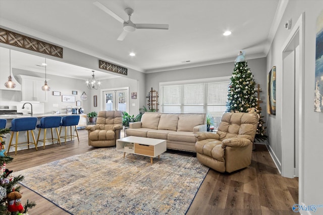 living room featuring french doors, ceiling fan with notable chandelier, crown molding, sink, and wood-type flooring