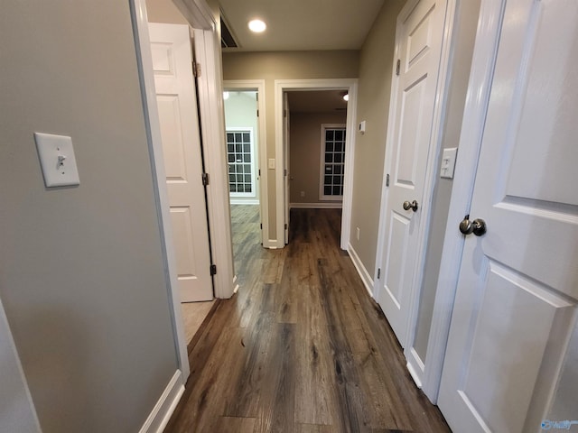 hallway featuring dark wood finished floors and baseboards