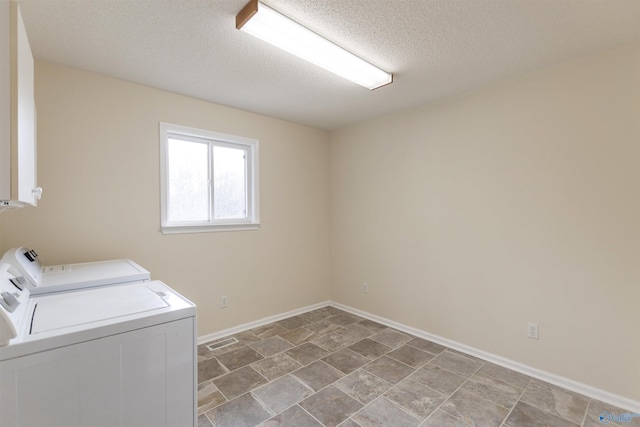 clothes washing area with washing machine and clothes dryer and a textured ceiling