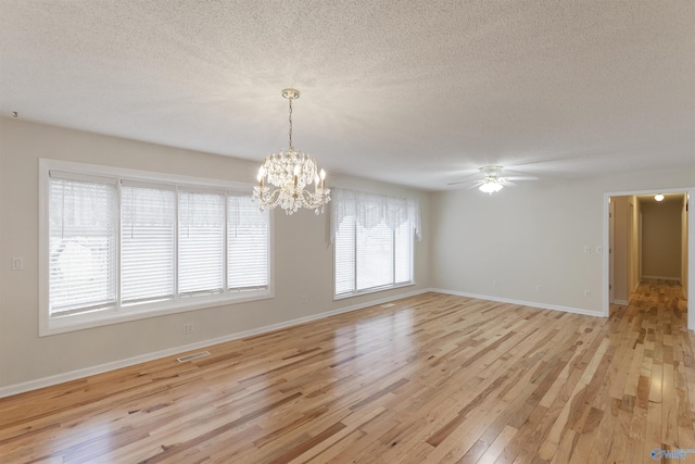 empty room featuring ceiling fan with notable chandelier, light hardwood / wood-style flooring, and a textured ceiling