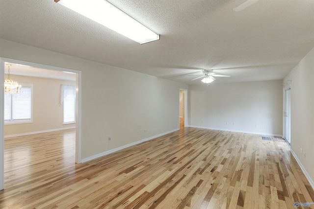 unfurnished room featuring ceiling fan with notable chandelier, a textured ceiling, and light hardwood / wood-style flooring