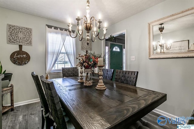 dining space with a textured ceiling, baseboards, a chandelier, and wood finished floors