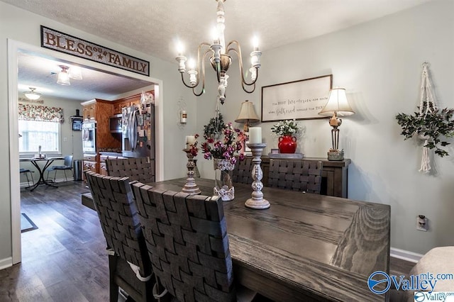 dining space with baseboards, a textured ceiling, wood finished floors, and an inviting chandelier