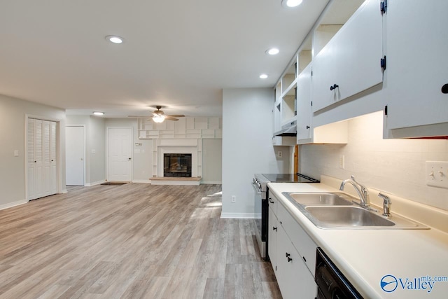 kitchen featuring sink, light wood-type flooring, stainless steel electric range, and white cabinets