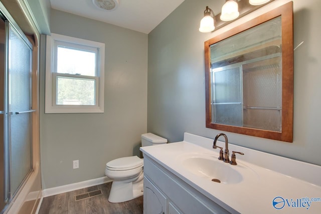 full bathroom with enclosed tub / shower combo, hardwood / wood-style floors, vanity, and toilet