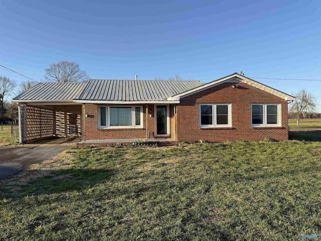 ranch-style home featuring a front lawn, aphalt driveway, metal roof, an attached carport, and brick siding