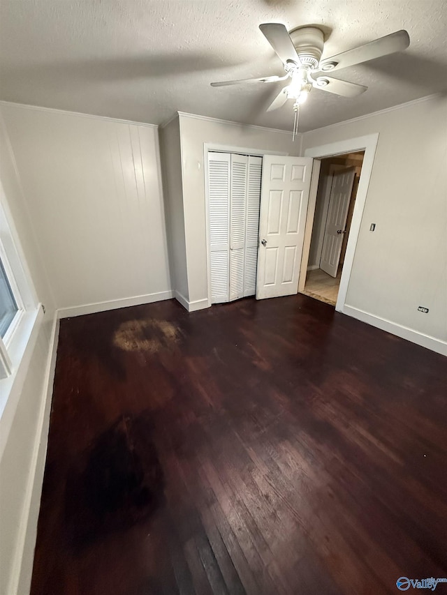 unfurnished bedroom with wood finished floors, baseboards, a closet, and a textured ceiling