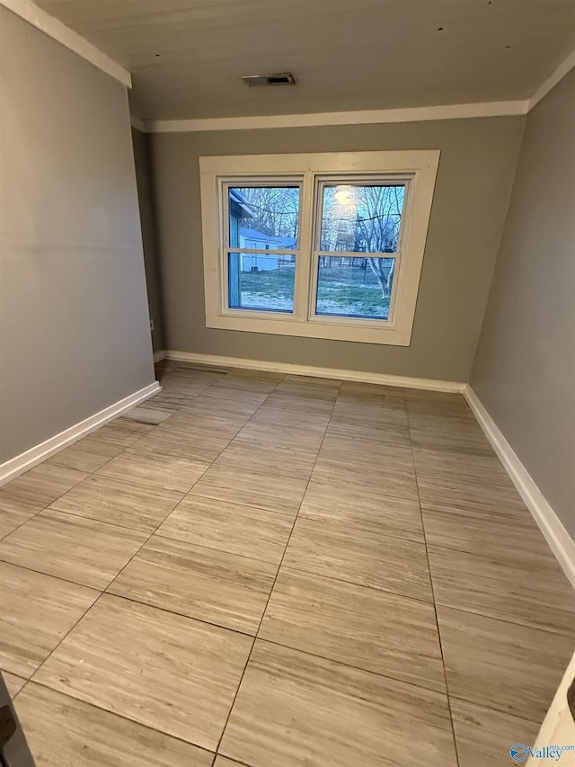 spare room featuring baseboards, visible vents, and ornamental molding