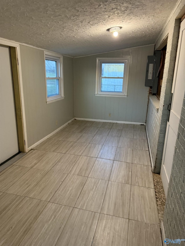 unfurnished bedroom with electric panel, multiple windows, and a textured ceiling