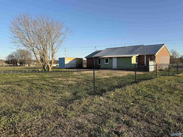 view of front of property featuring metal roof, brick siding, a front yard, and fence