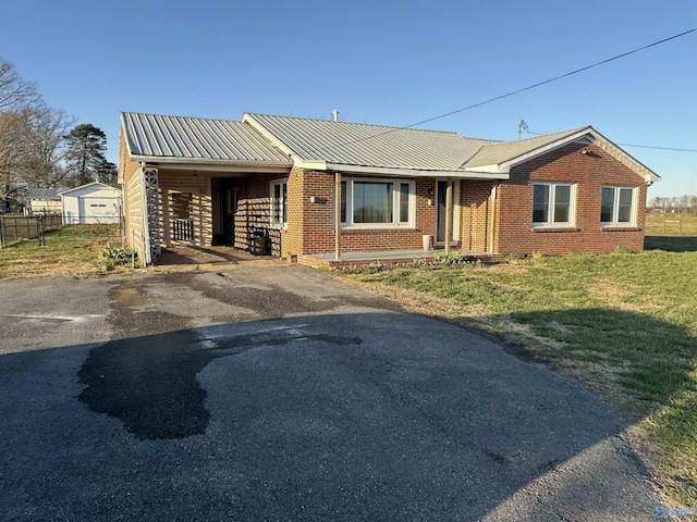 view of front of property with a front yard, fence, driveway, brick siding, and metal roof