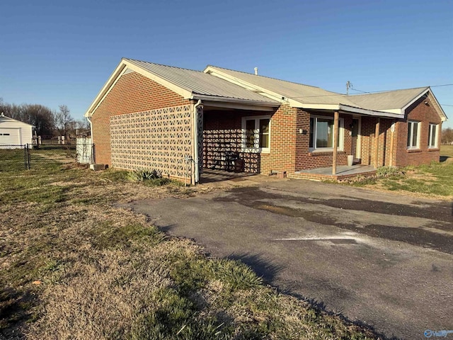 view of property exterior featuring fence, brick siding, and metal roof