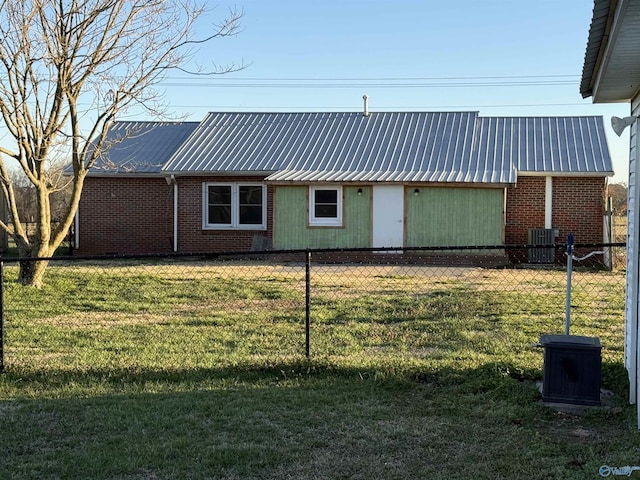 exterior space featuring brick siding, metal roof, a yard, and fence