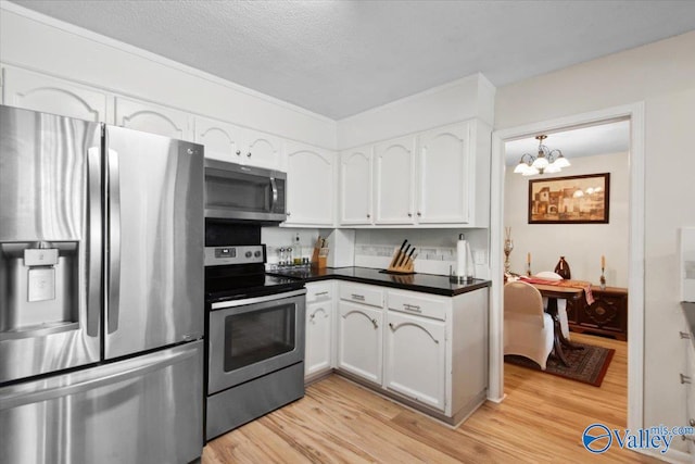 6304 Cedar Point Dr, Huntsville, AL 35810 - kitchen with appliances with stainless steel finishes, white cabinets, light wood-style floors, dark countertops, and a chandelier