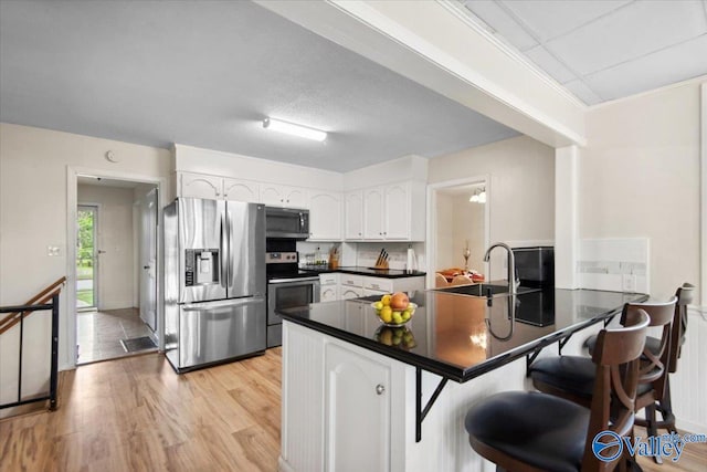 6304 Cedar Point Dr, Huntsville, AL 35810 - kitchen featuring stainless steel appliances, dark countertops, a peninsula, white cabinets, and light wood finished floors