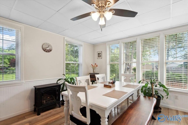 6304 Cedar Point Dr, Huntsville, AL 35810 - dining area featuring wood finished floors, a wood stove, ceiling fan, plenty of natural light, and a wainscoted wall
