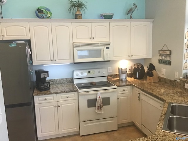 kitchen with light tile patterned floors, white cabinets, white appliances, and a sink