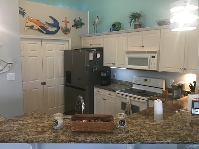 kitchen featuring dark stone counters, white appliances, a peninsula, and white cabinetry