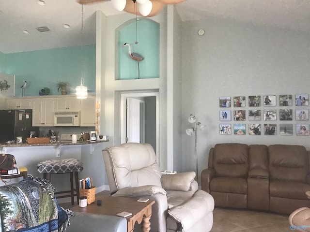 tiled living area with visible vents, a high ceiling, and ceiling fan