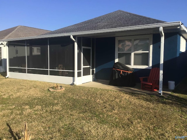 back of house featuring a sunroom, a lawn, and roof with shingles