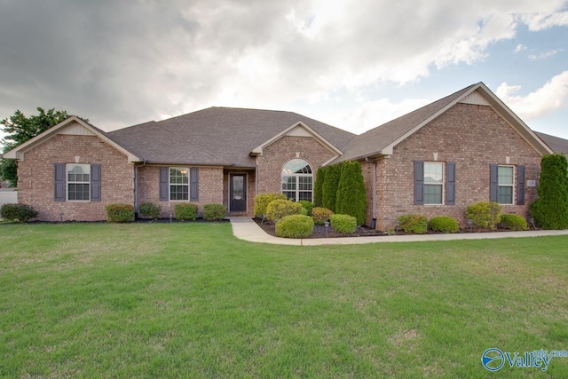 ranch-style home with a front lawn, brick siding, and roof with shingles