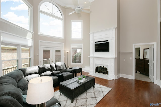 living room with ceiling fan, hardwood / wood-style flooring, a healthy amount of sunlight, and a towering ceiling