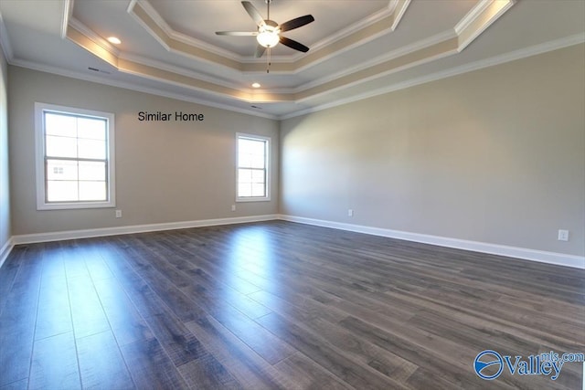 unfurnished room with a tray ceiling, dark wood-type flooring, and ornamental molding