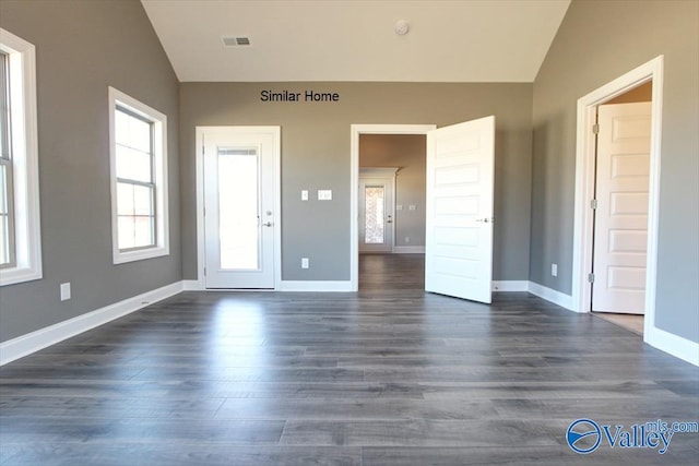 spare room with dark wood-type flooring and lofted ceiling