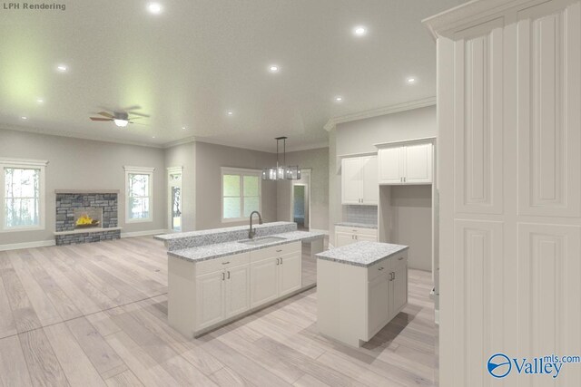 kitchen featuring white cabinetry, a center island with sink, decorative light fixtures, and sink