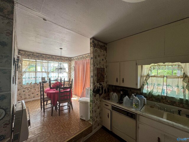 kitchen featuring an inviting chandelier, a textured ceiling, dishwasher, and sink