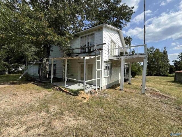 rear view of house featuring a deck, a yard, and a patio area