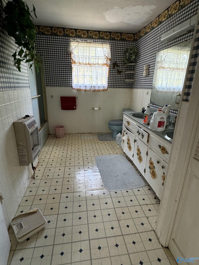 bathroom with tile walls, heating unit, a healthy amount of sunlight, and toilet