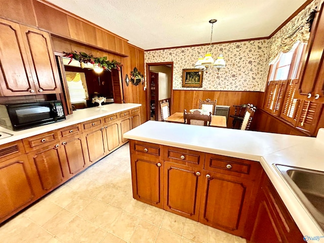 kitchen with ornamental molding, light tile patterned flooring, a textured ceiling, and kitchen peninsula